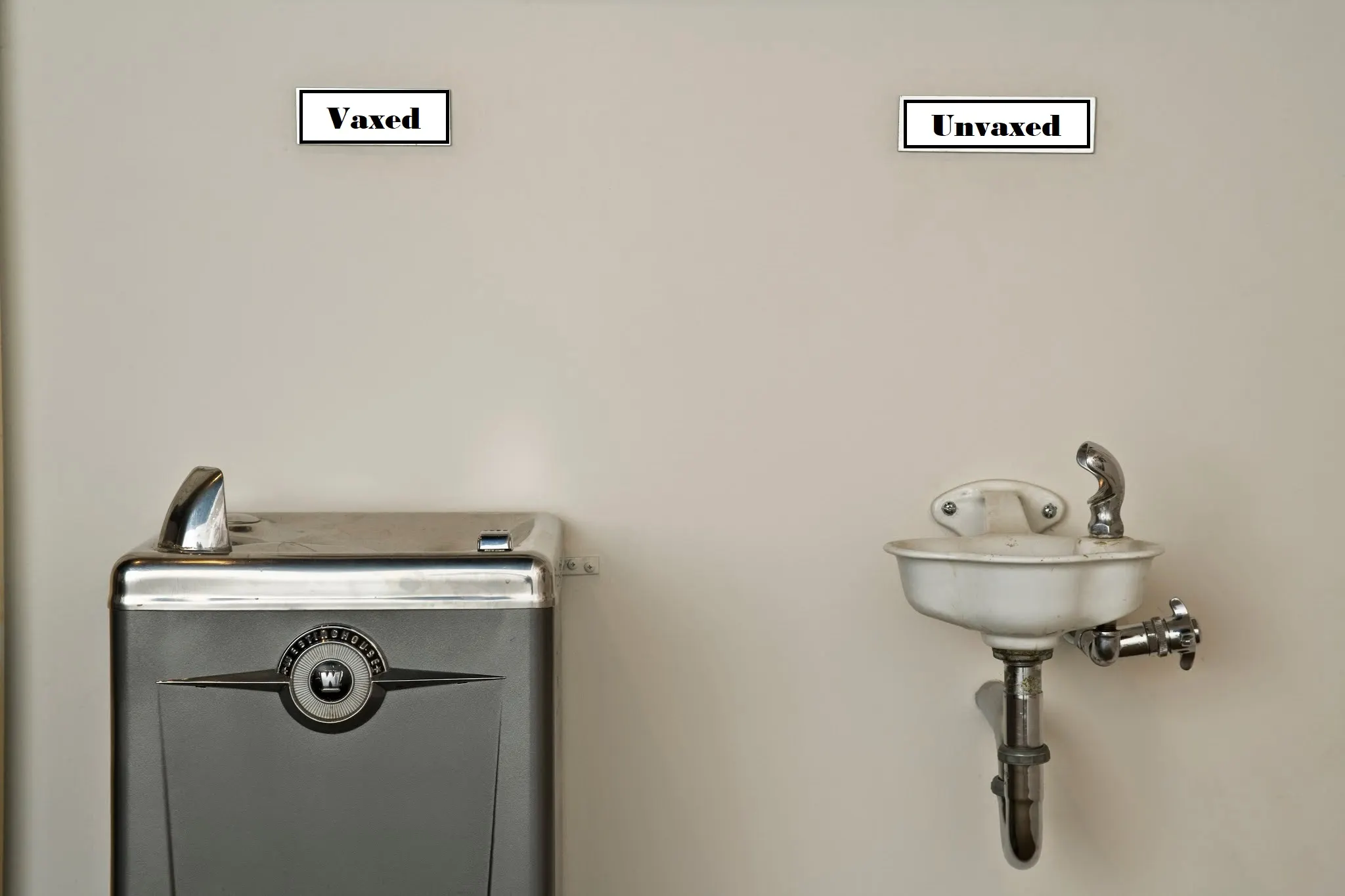 Two drinking fountains in a school hallway with institutional signage above them.